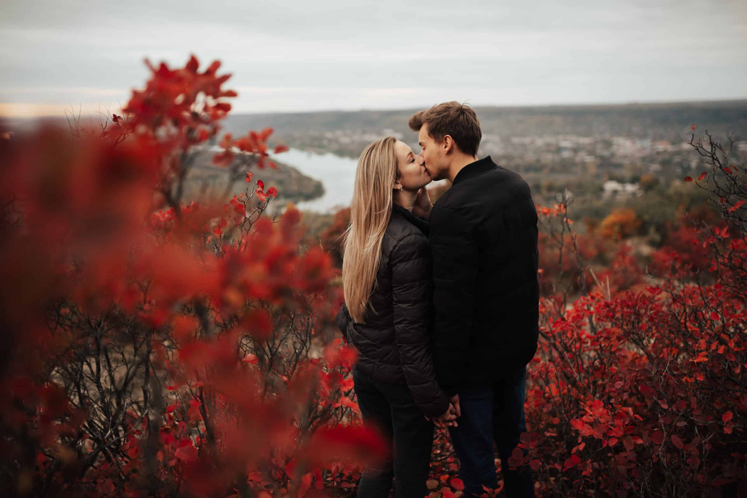 Couple kissing and hugging on scenic autumn hills