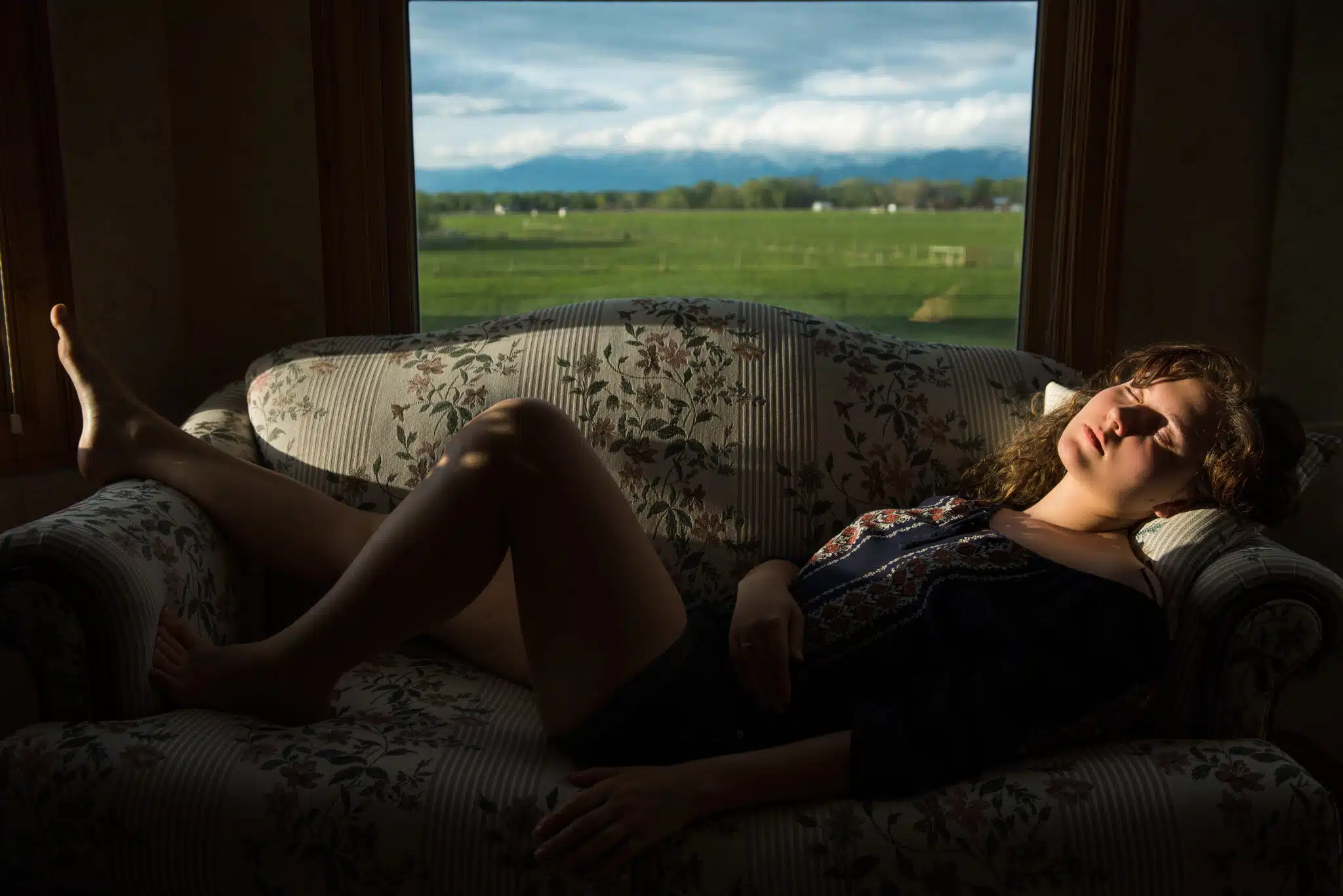 Young woman sleeping on sofa in rural country house with sunligh