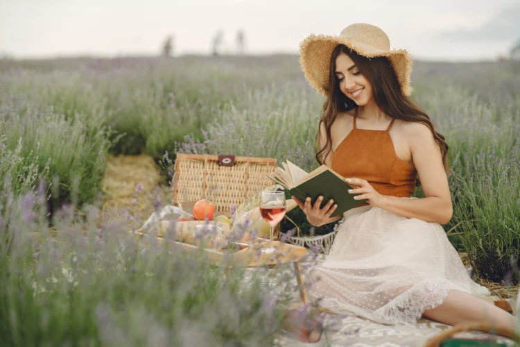 woman in a straw hat in a lavender field reading a book