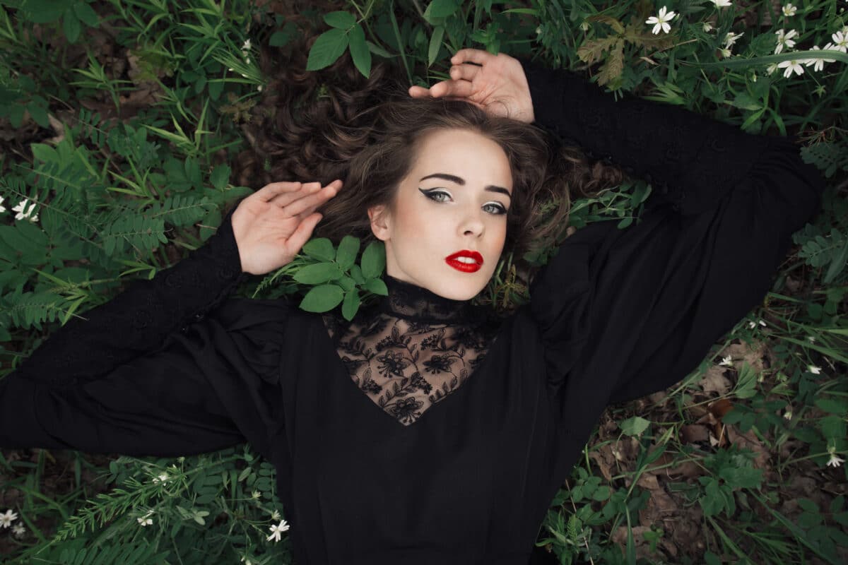 Young woman in a black dress lying in the grass
