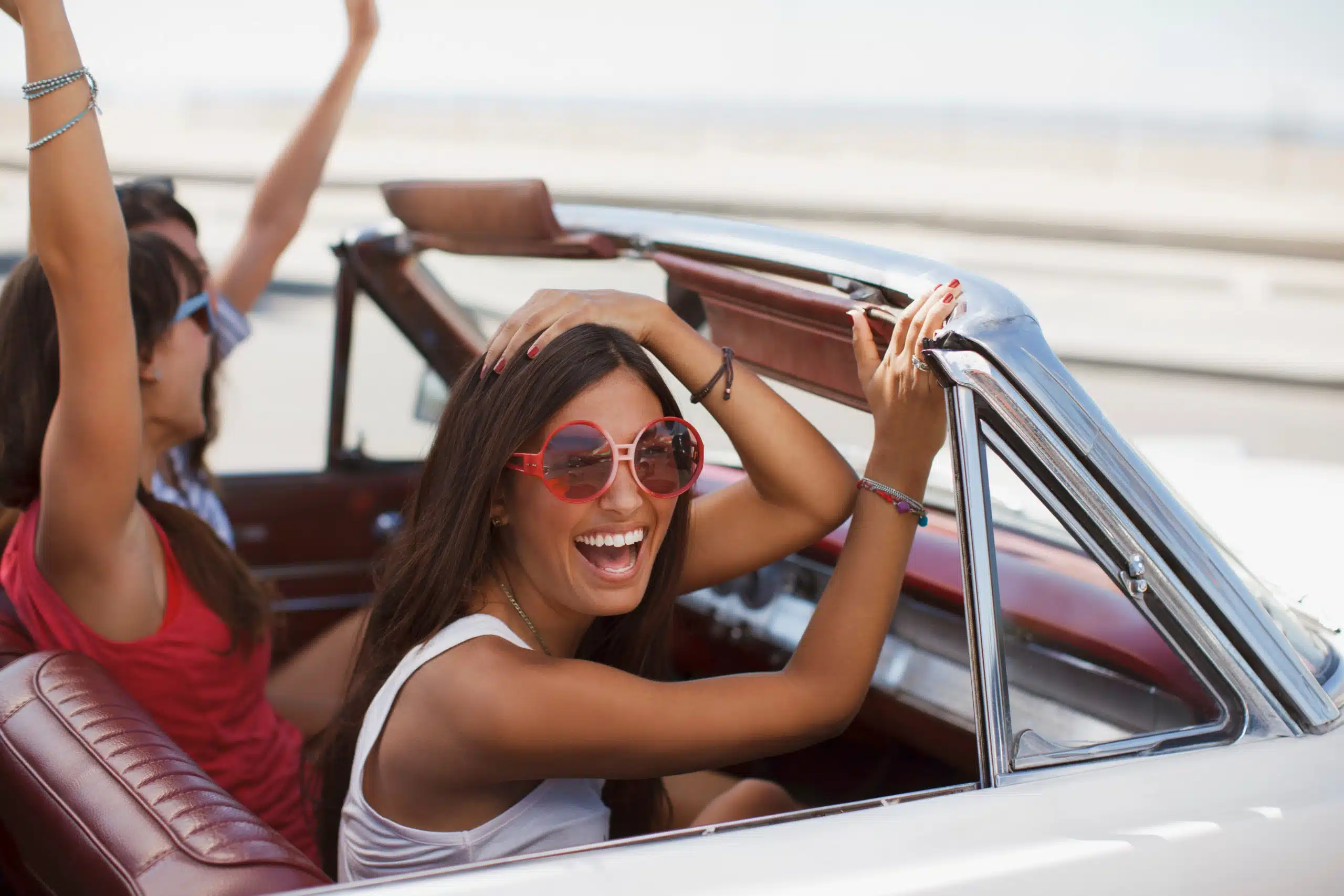 Smiling and laughing women driving convertible