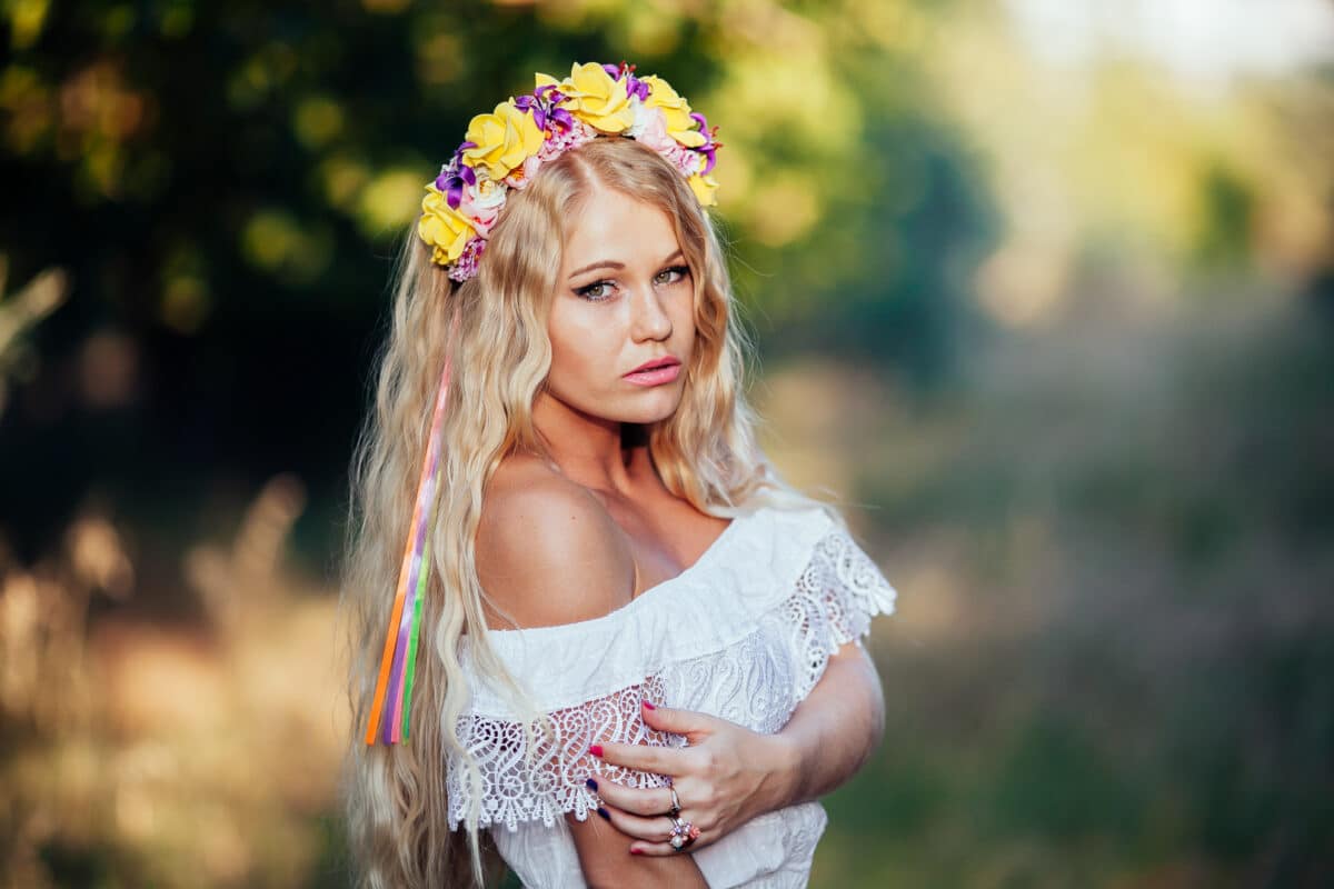 a blonde girl wearing  white dress with flower wreath