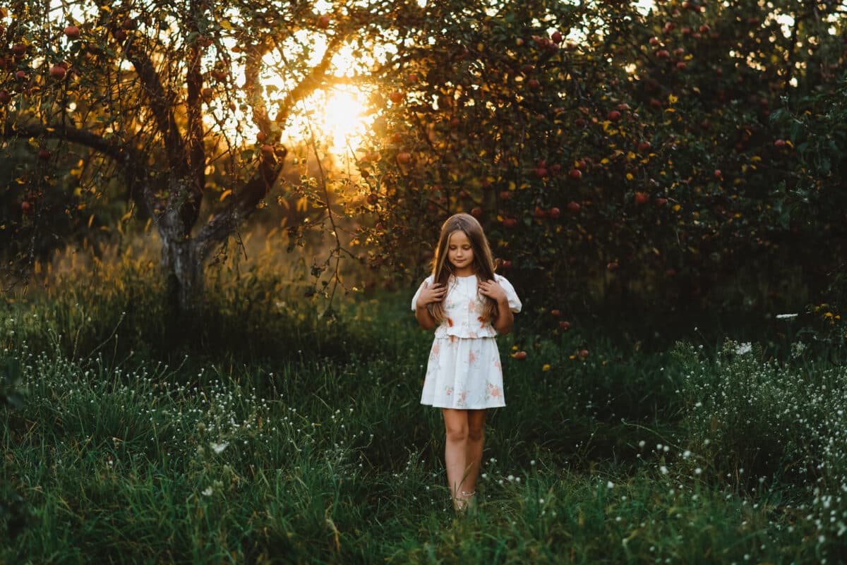 A beautiful little girl is walking at sunset in the garden