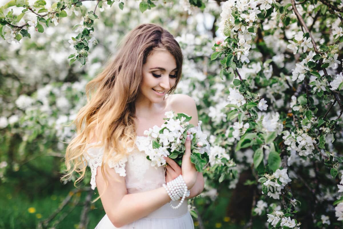 a beautiful maiden in white dress enjoying the blooming apple trees