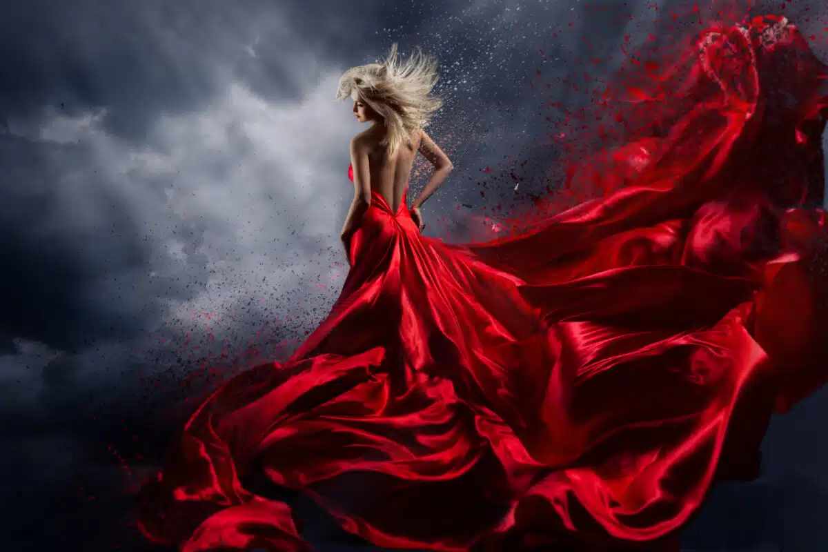 Woman in a red dress dancing over the storm sky