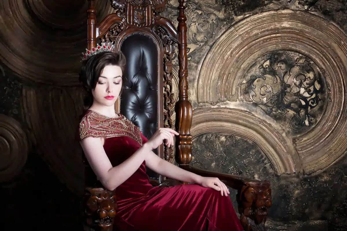 powerful and confident queen in a red dress sitting on throne