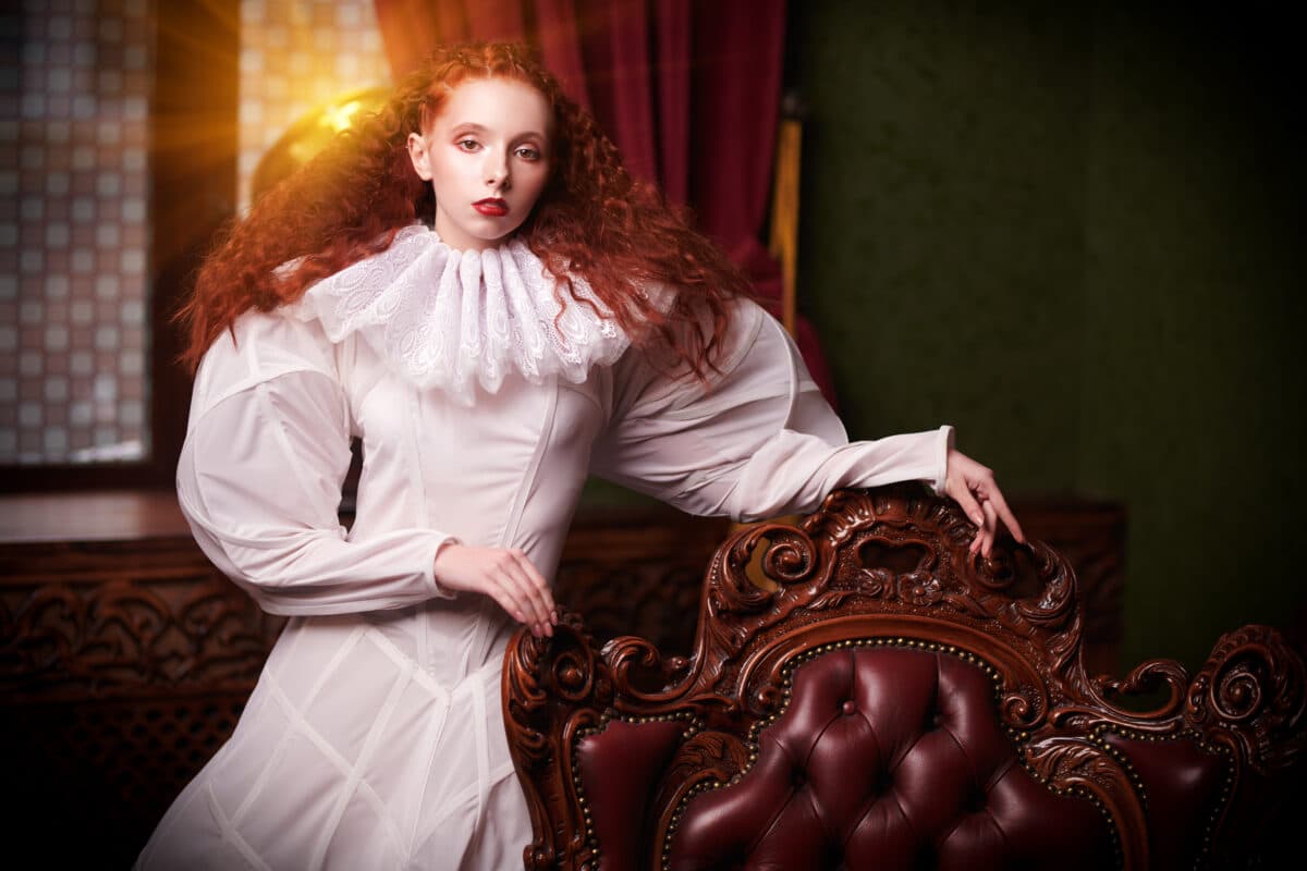 renaissance redhead royal lady standing next to a luxury chair