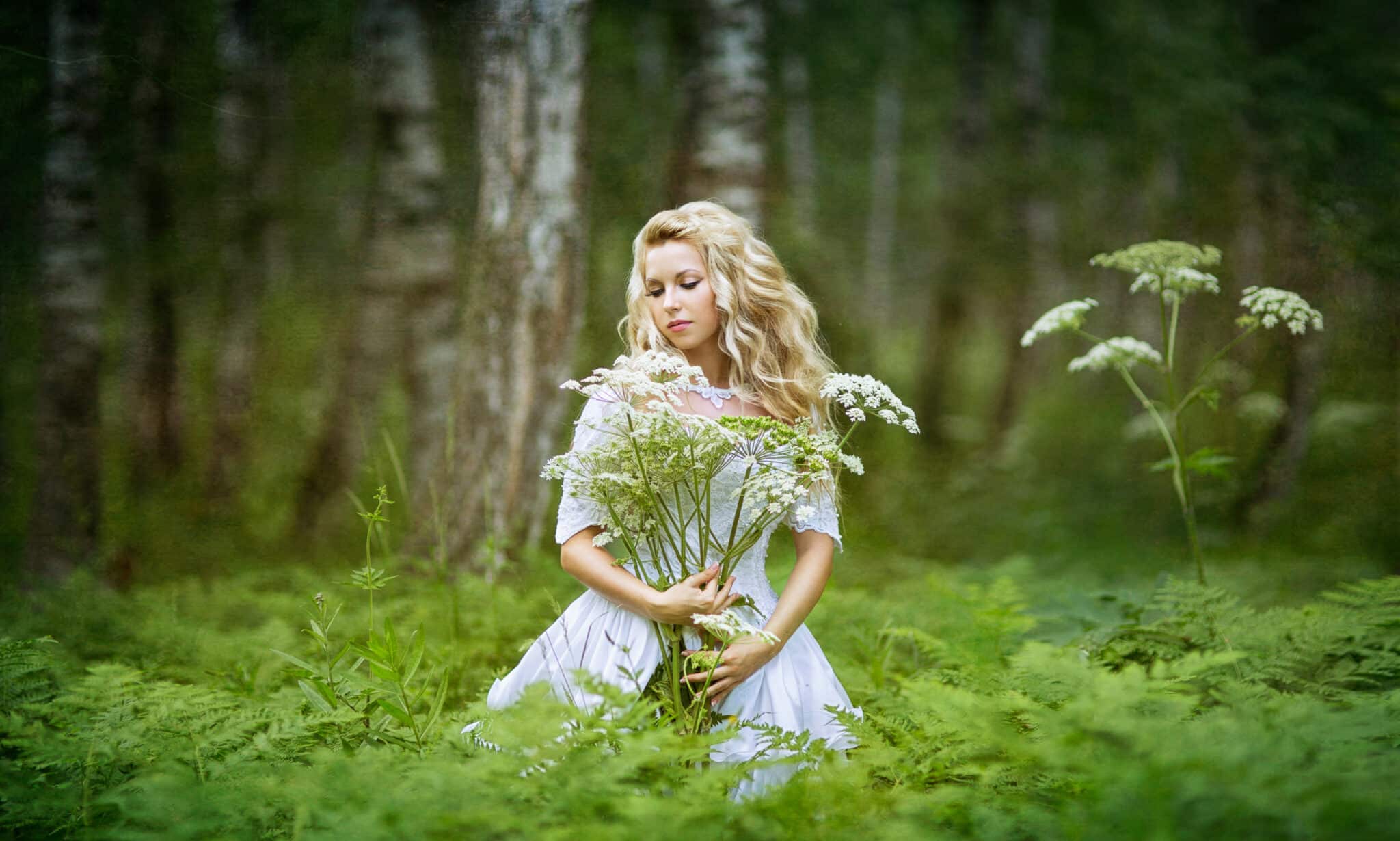 beautiful lady holding a bouquet of wildflowers in the woods