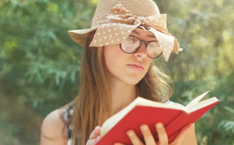 Beautiful country girl reading a book in nature, enjoying a sunny day. 