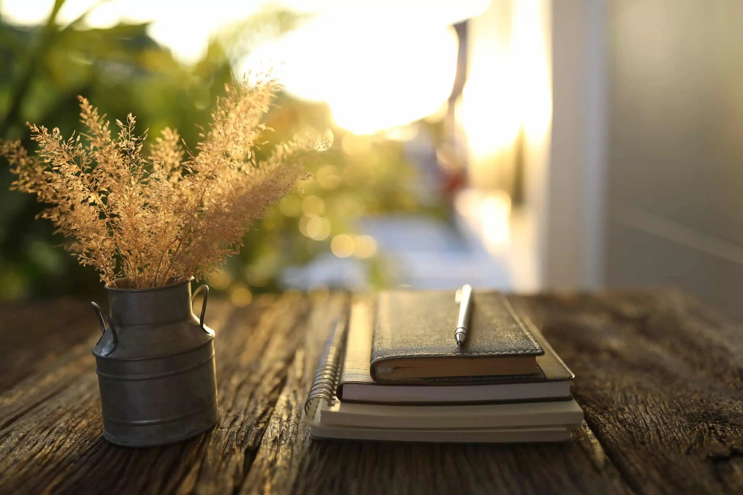 dry grass flower in stainless vase and notebooks by the window.