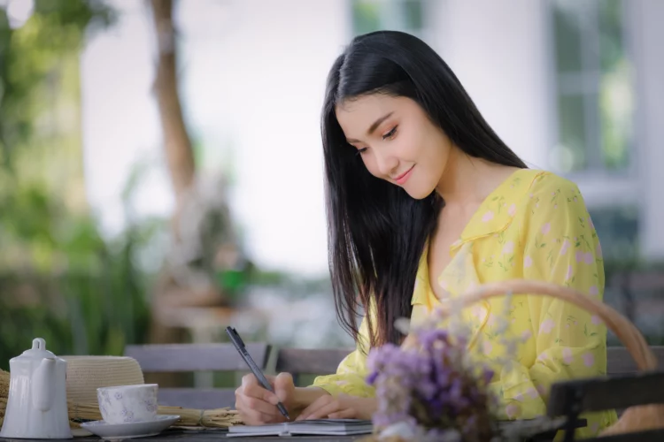 young woman writing on notepad in the garden.
