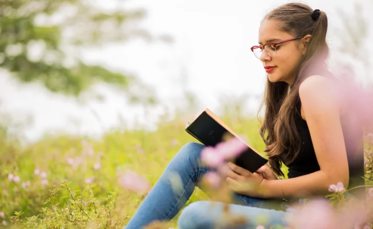 Beautiful young lady reading in the park