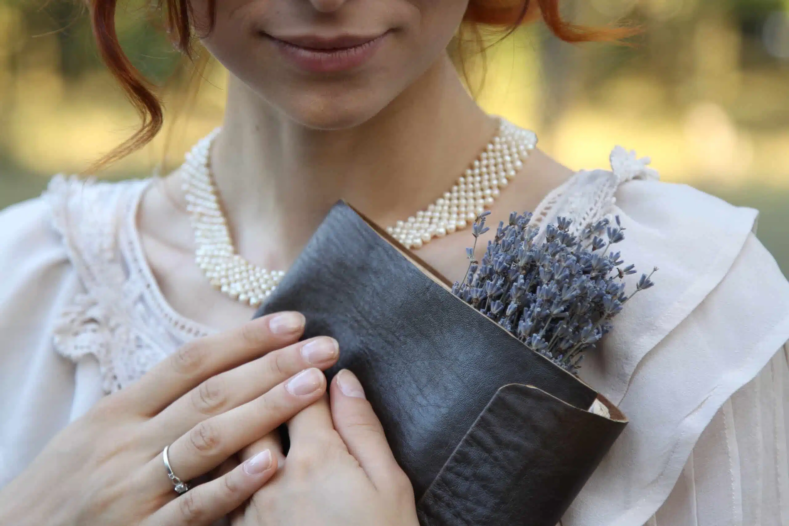 Beautiful redhead in a vintage dress holding a book with lavender flowers.