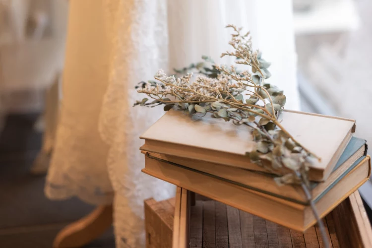 a stack of books with flowers on top of a wooden stool.