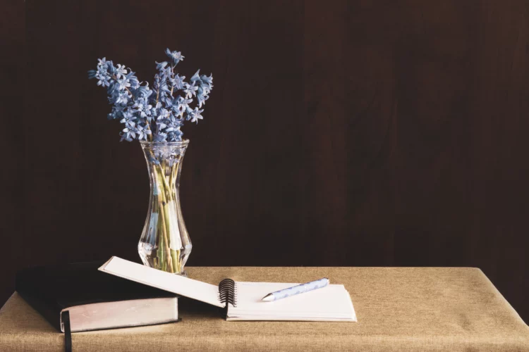 journal placed on a table with purple flowers in vase