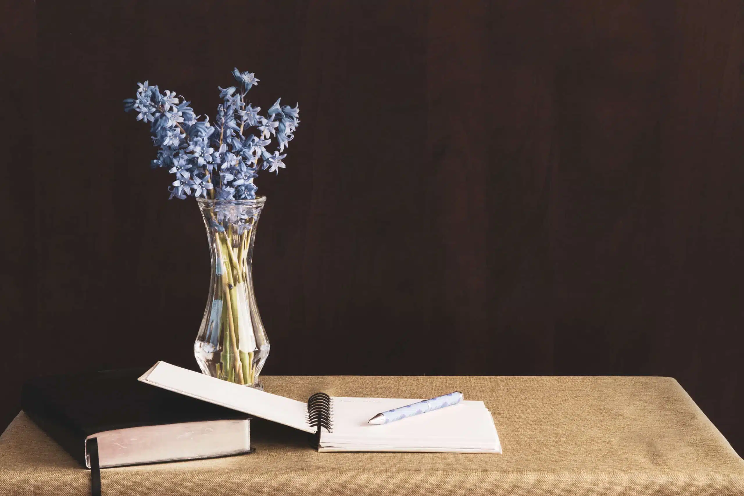 journal placed on a table with purple flowers in vase