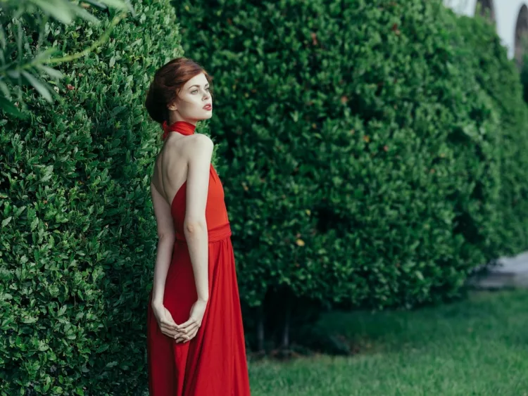 attractive woman in red dress outdoors in manicured garden
