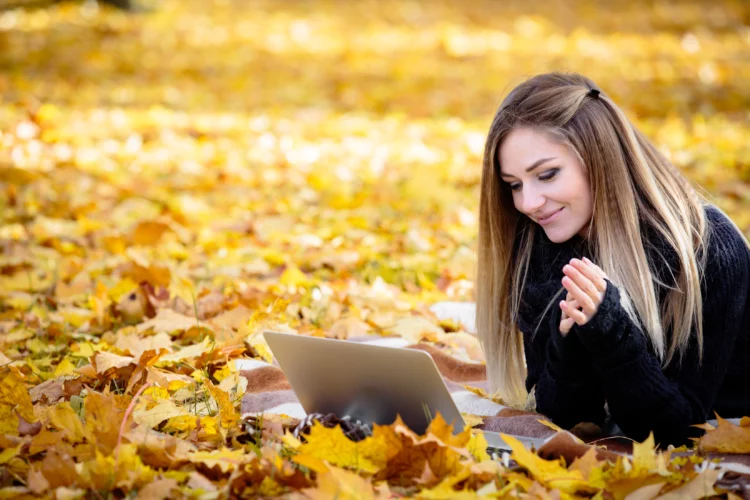 young woman working on laptop in autumn Park