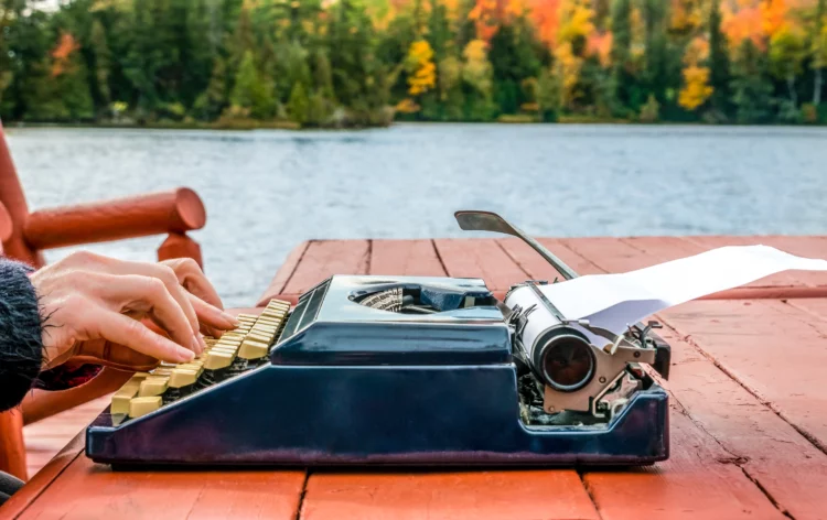 author working on a vintage typewriter by the lake