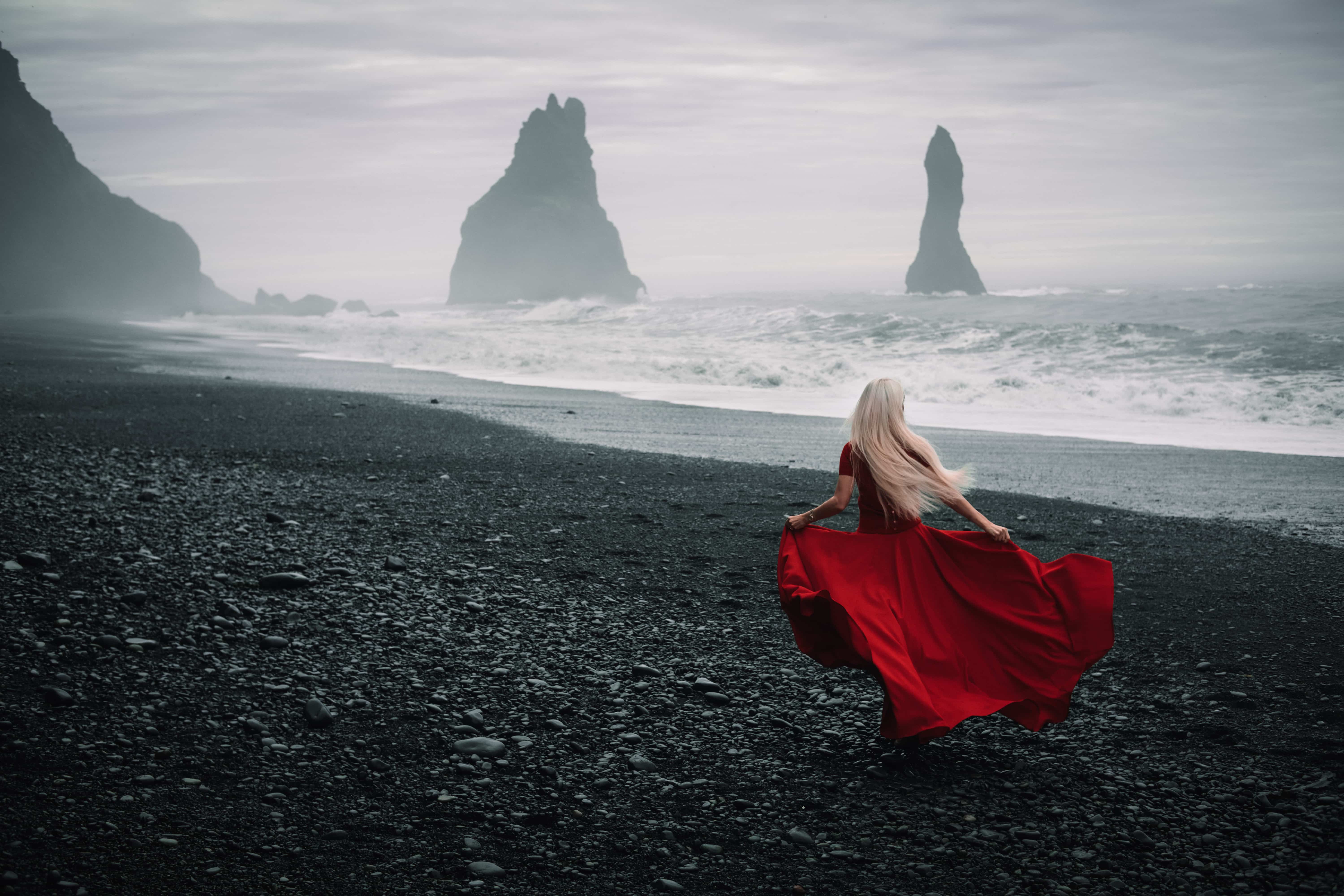 woman in red dress runs on the beach