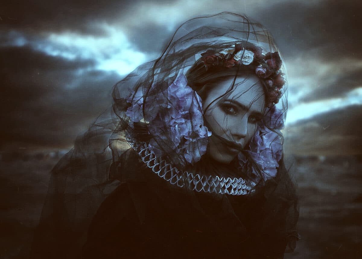 a dark mysterious lady wearing a veil and flower wreath on her head 