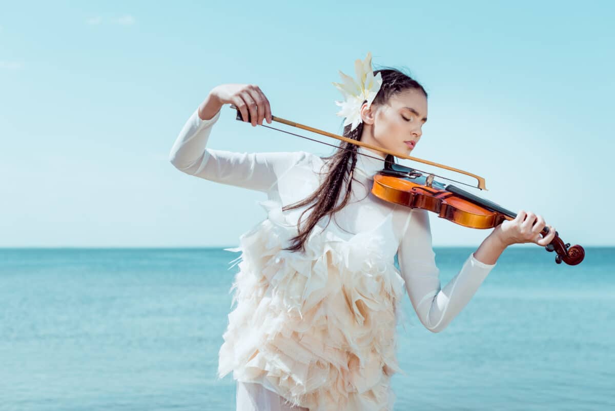tender woman in white swan costume playing on violin