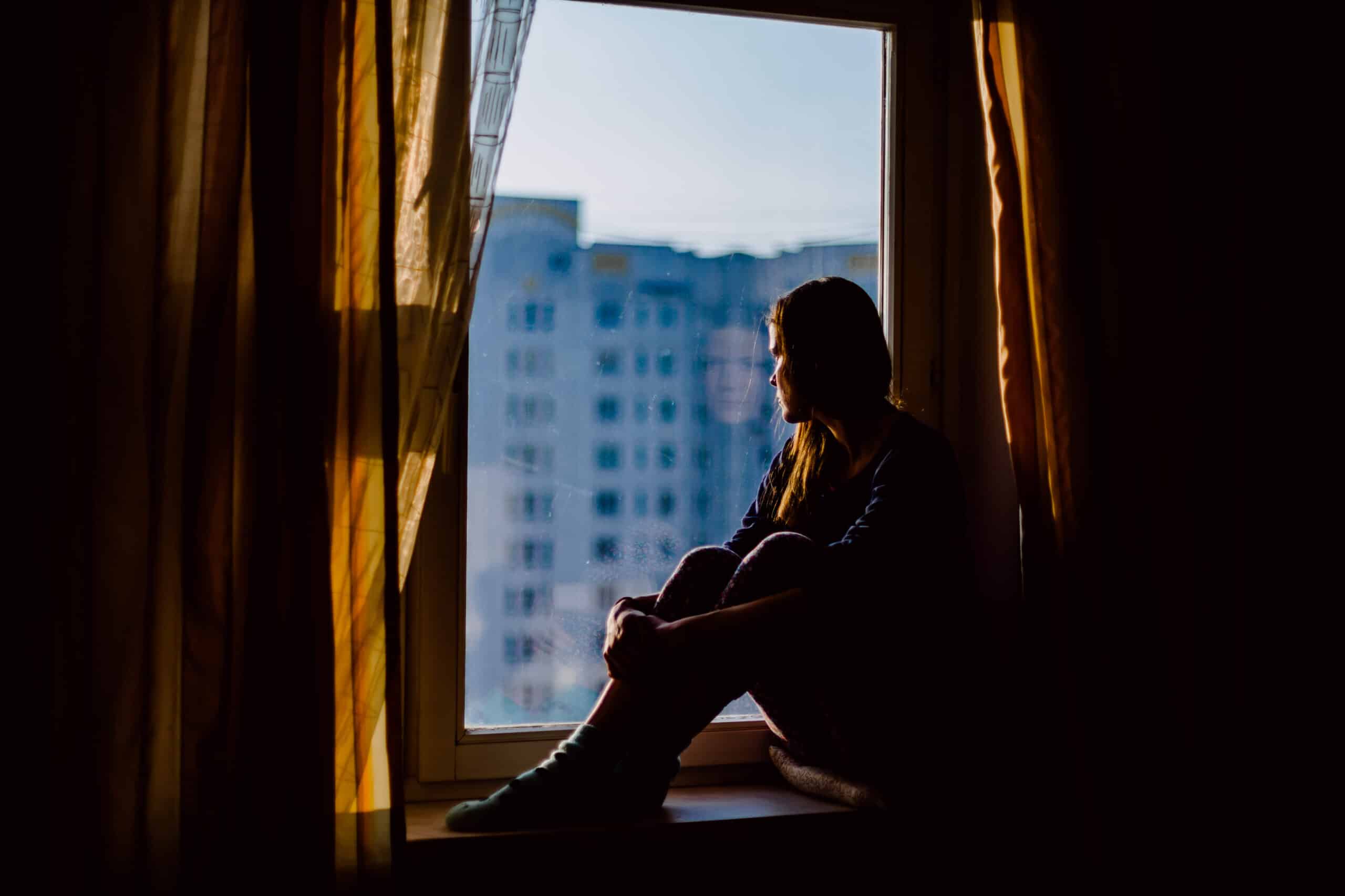Portrait of Beautiful Thoughtful Woman Relaxing on a Window Sill