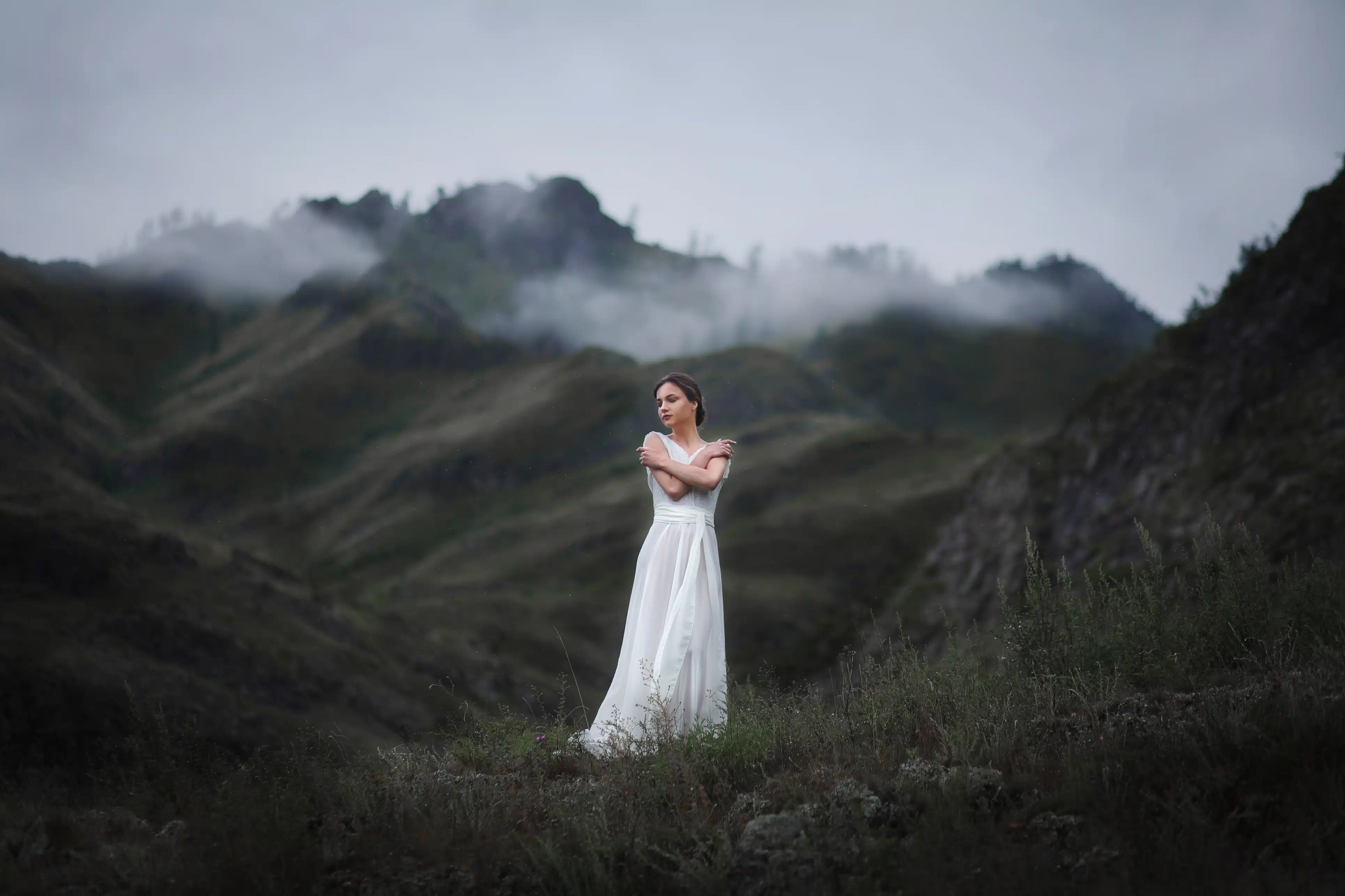 beautiful girl in a white dress walks in a foggy forest