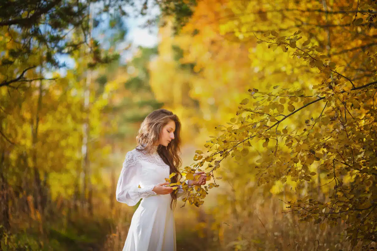 beautiful woman in a vintage dress walks in the autumn forest