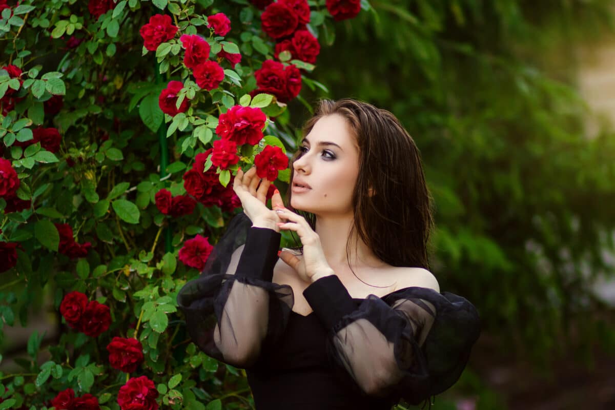beautiful lady in black standing in the rose garden
