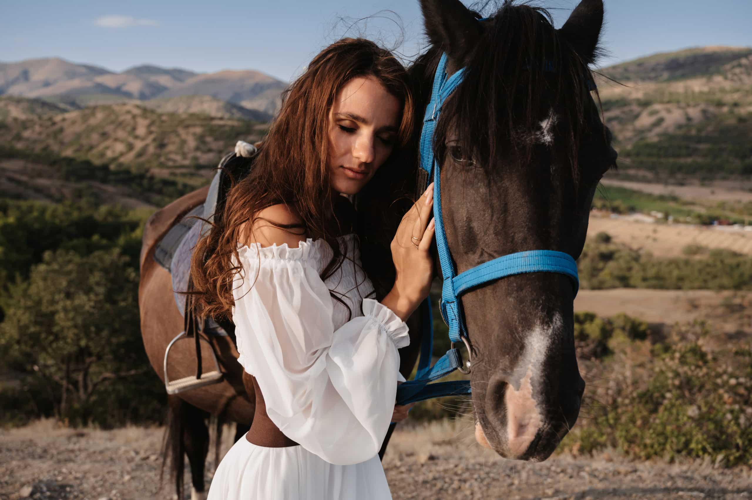 romantic girl hugs her horse on a mountain.