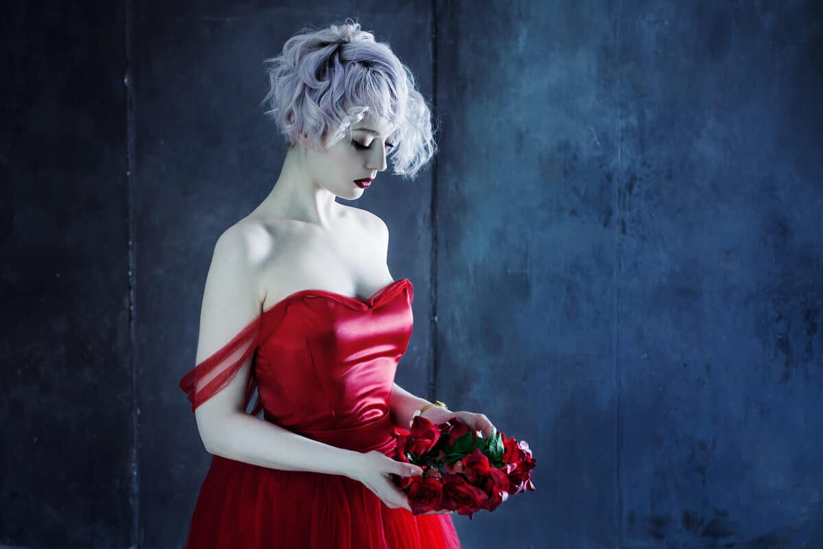 young magnificent woman in red dress holds a wreath of roses