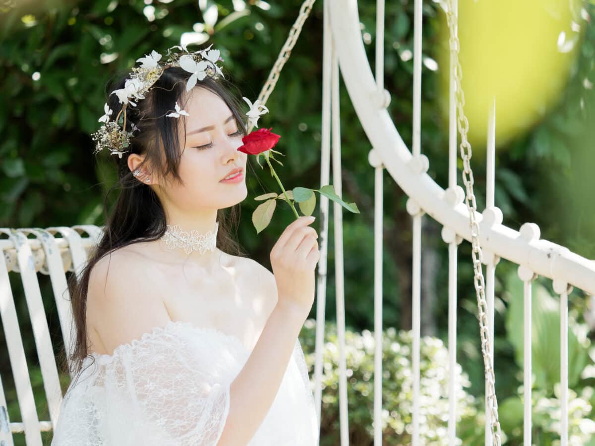 a pretty fairy lady in a beautiful white dress and head wreath, holding a red rose in hand
