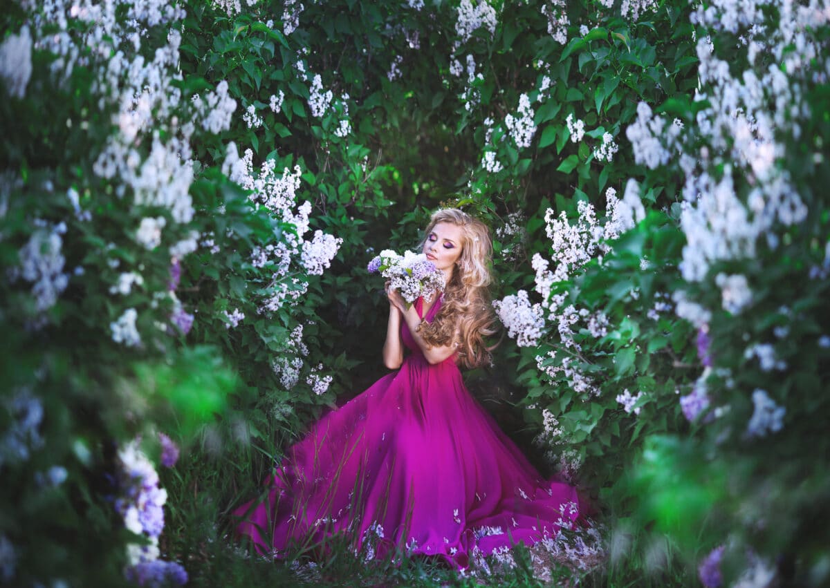 Beautiful girl in lilac dress in flower garden