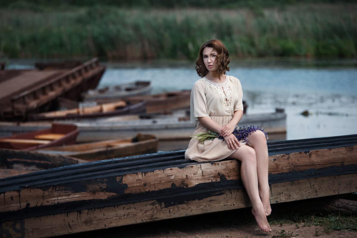 a pretty young woman sitting in the boat on river bank