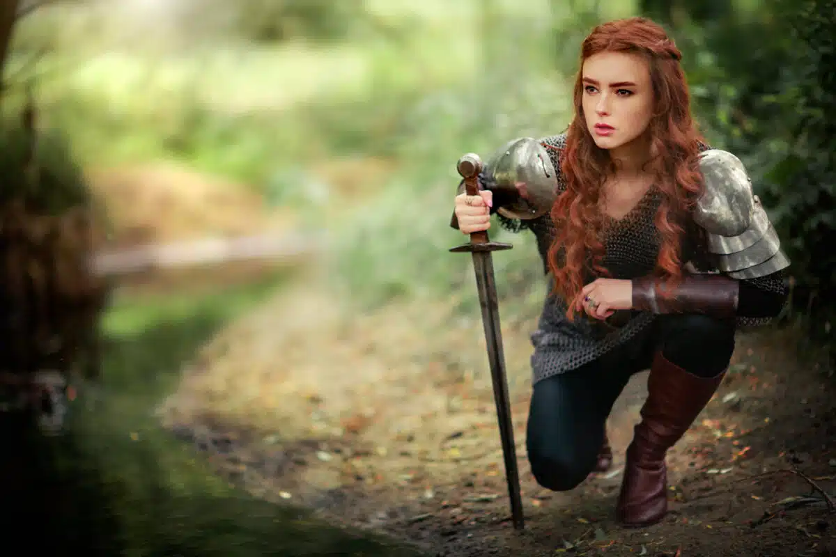 Beautiful red haired female warrior in medieval armor with a sword