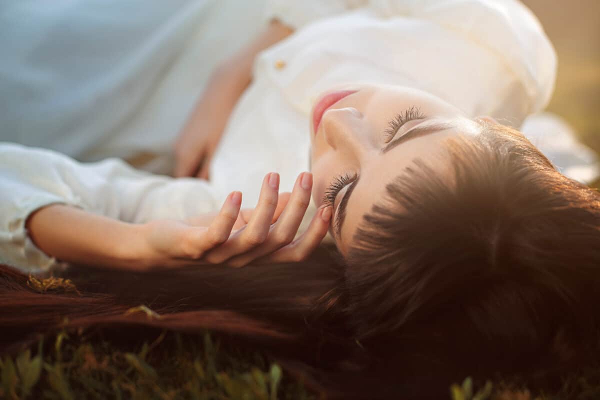 lonely woman lying on the meadow in soft sunset light
