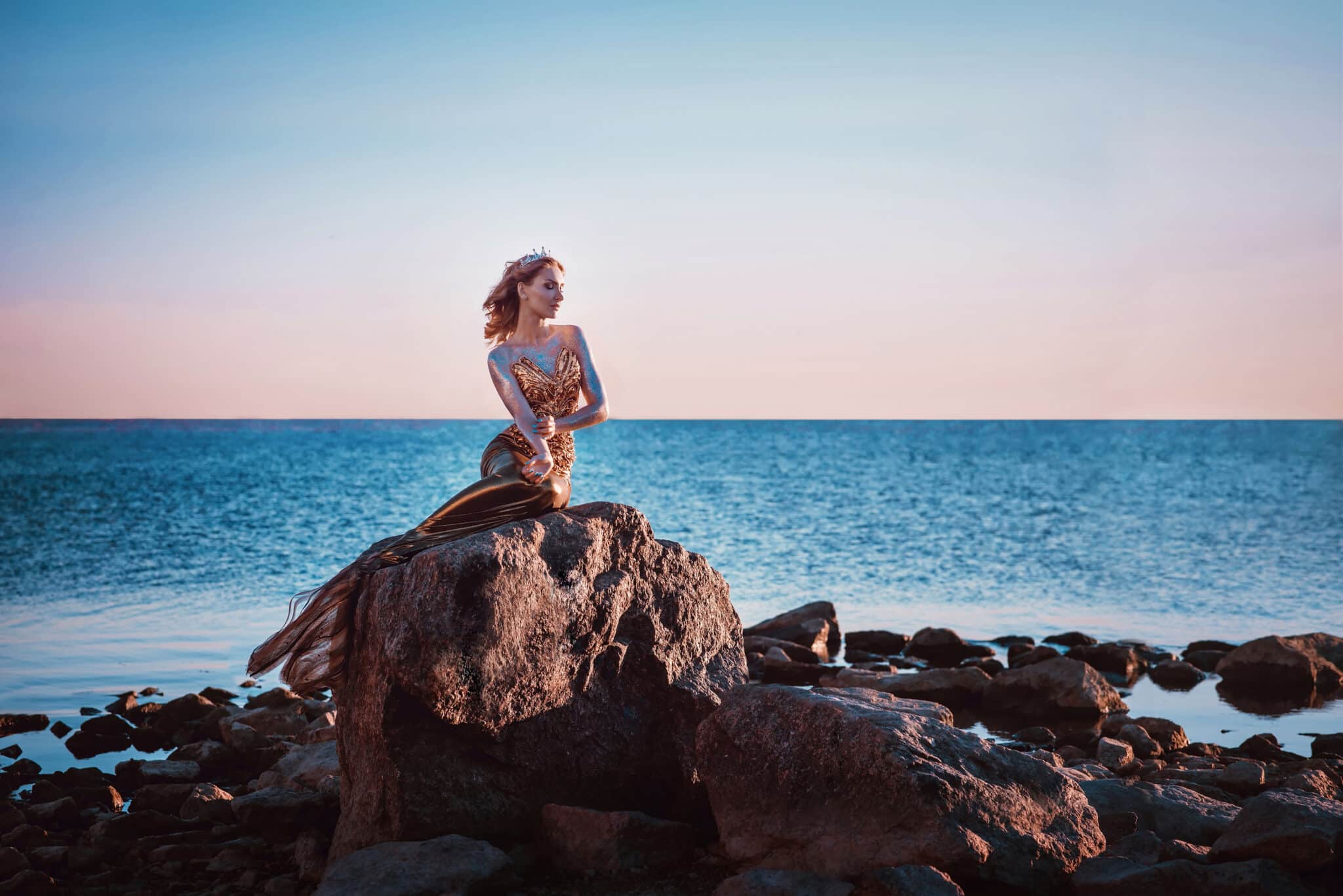 sad lonely mermaid sitting atop a high rock by the ocean