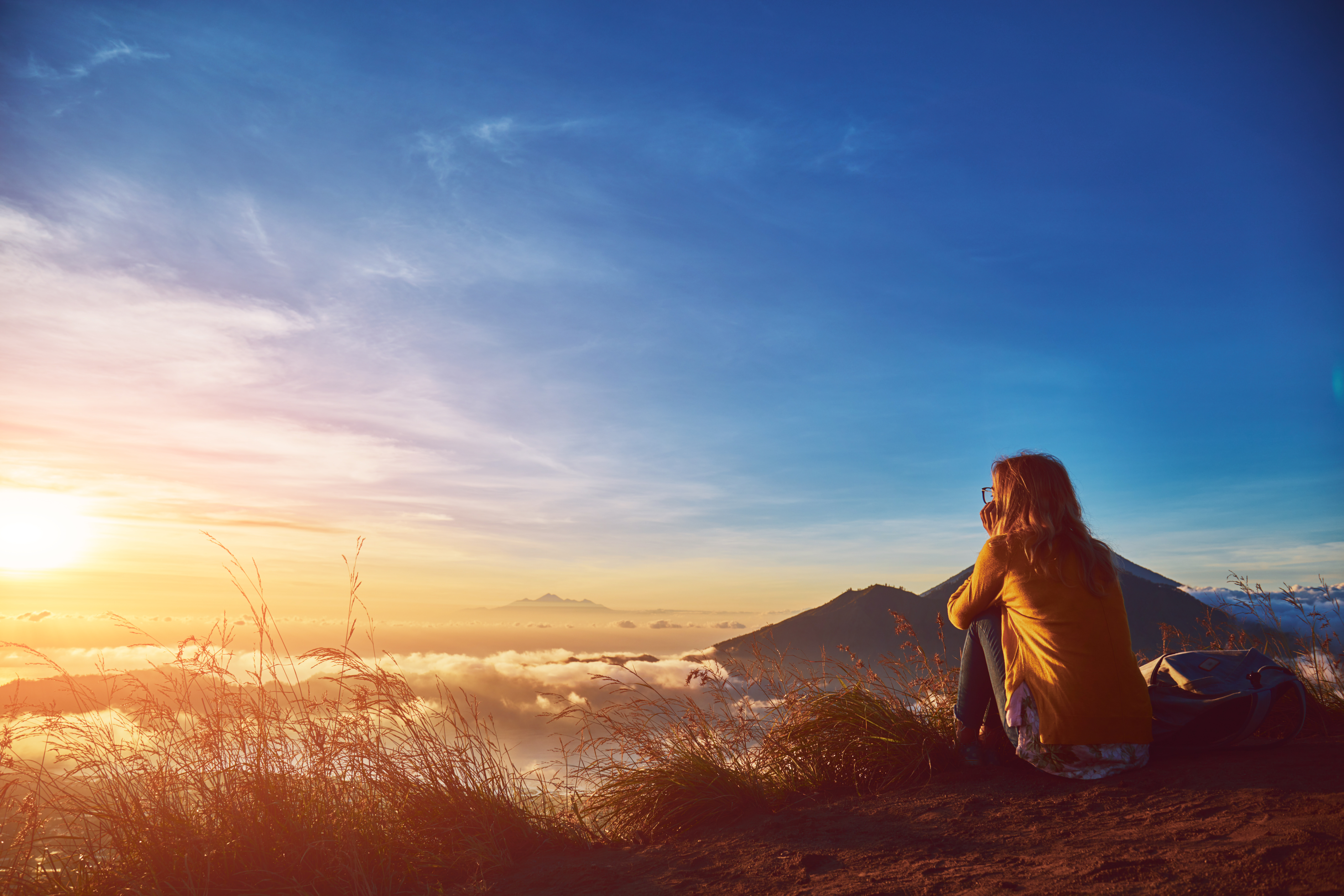 Woman alone enjoys the sunrise from a top of mountain
