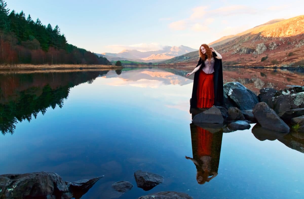 beautiful woman with red hair reflected in a still lake
