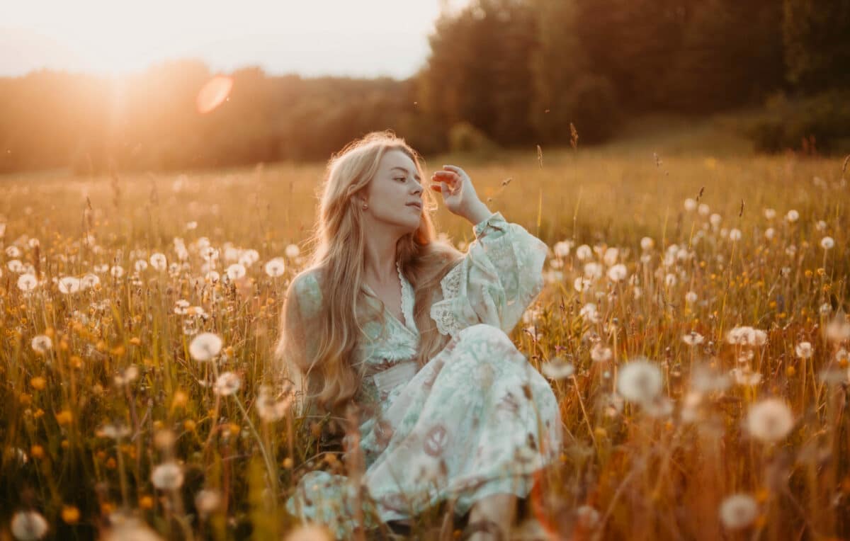 woman in a dress relaxing in the summer in the field at sunset