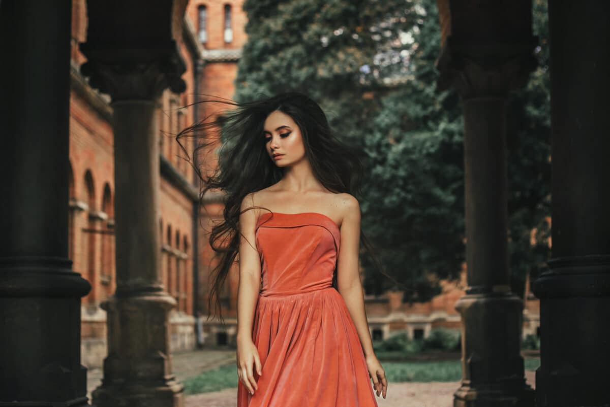 Beautiful brunette girl, with very long hair, in an orange, vintage dress