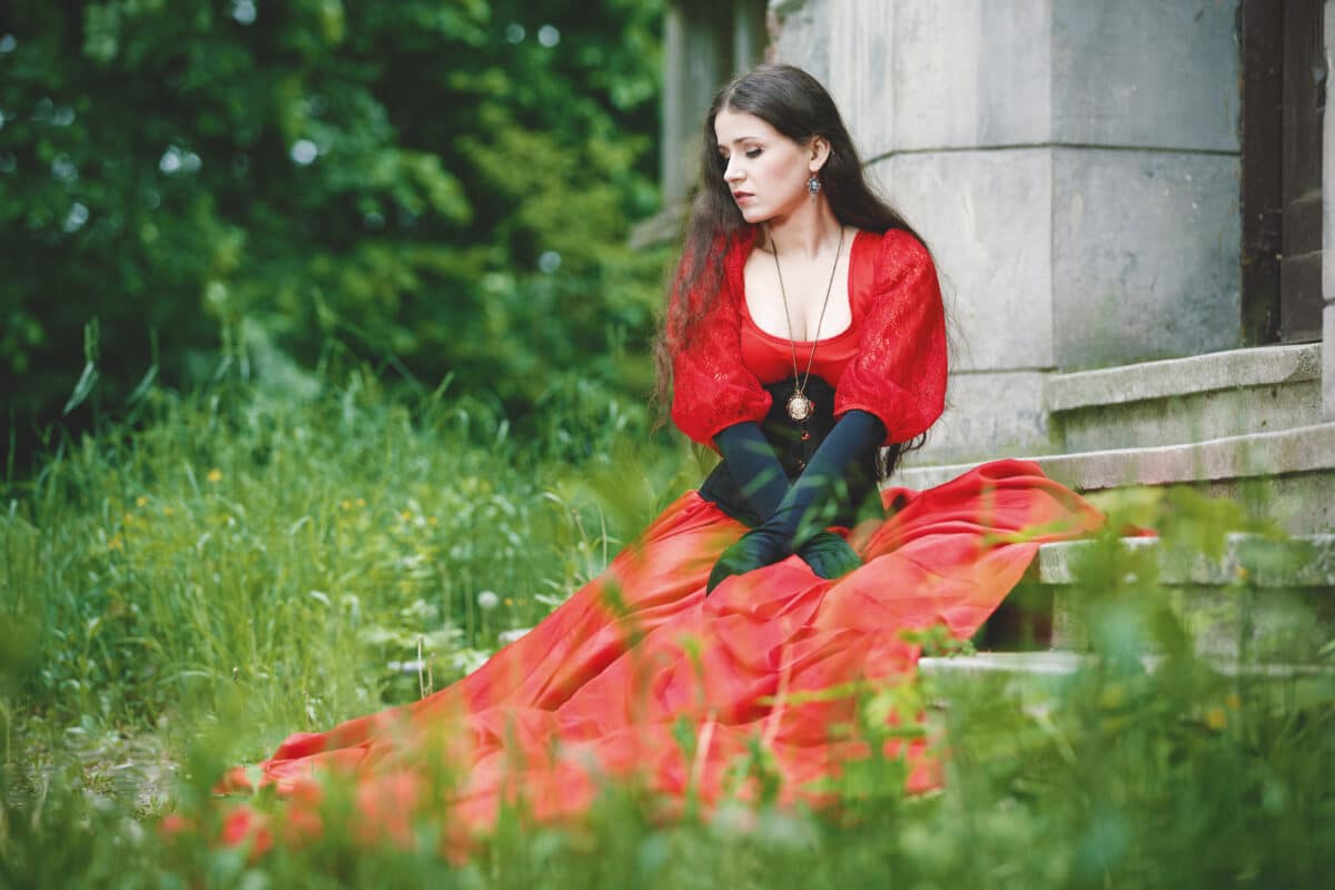 Woman in red Victorian dress sitting on the stairs