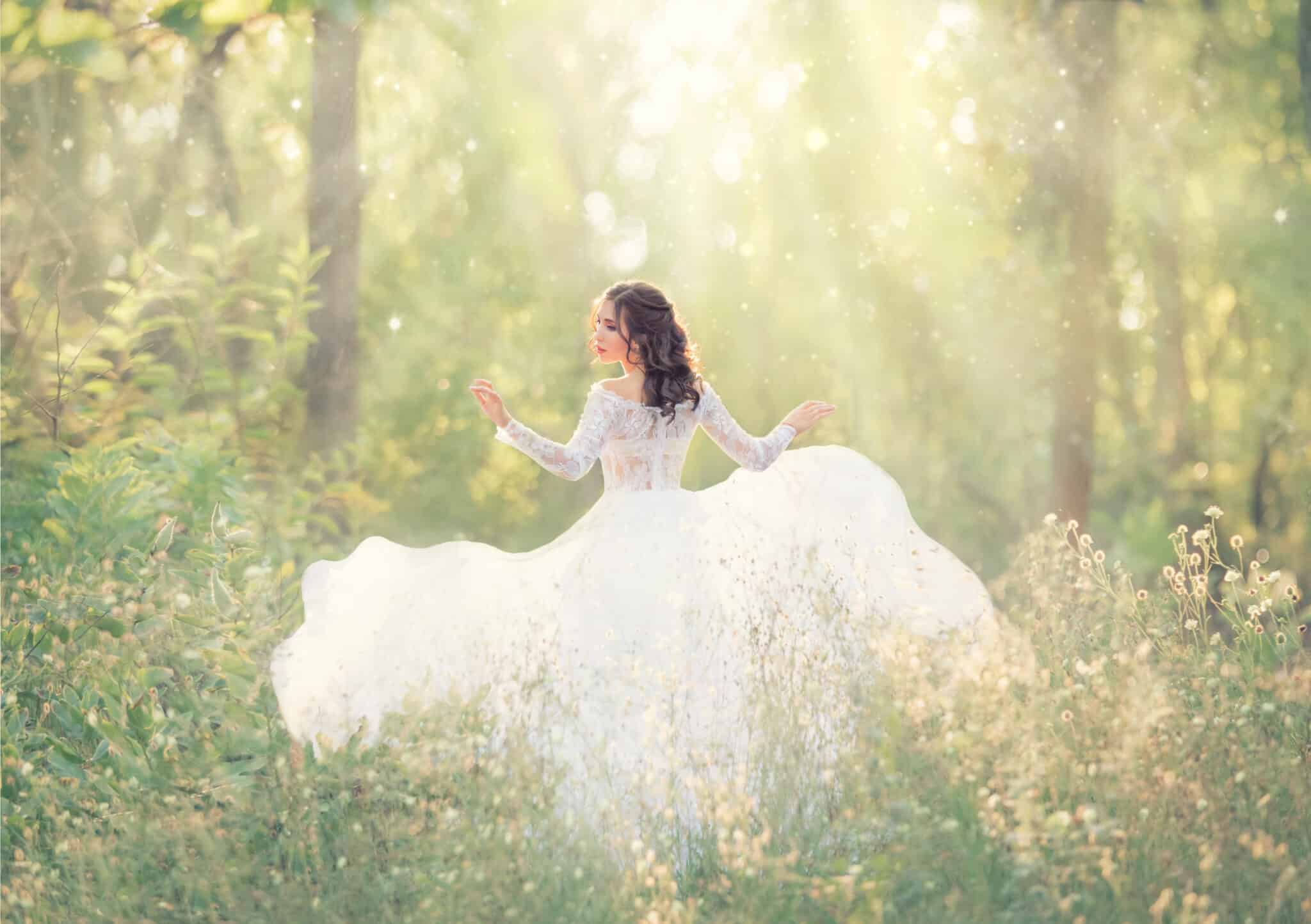 elegant and tender girl with black hair in white elegant light dress, lady runs in forest, turning pretty face on camera, her long train flying and fluttering in wind in bright rays of sunlight