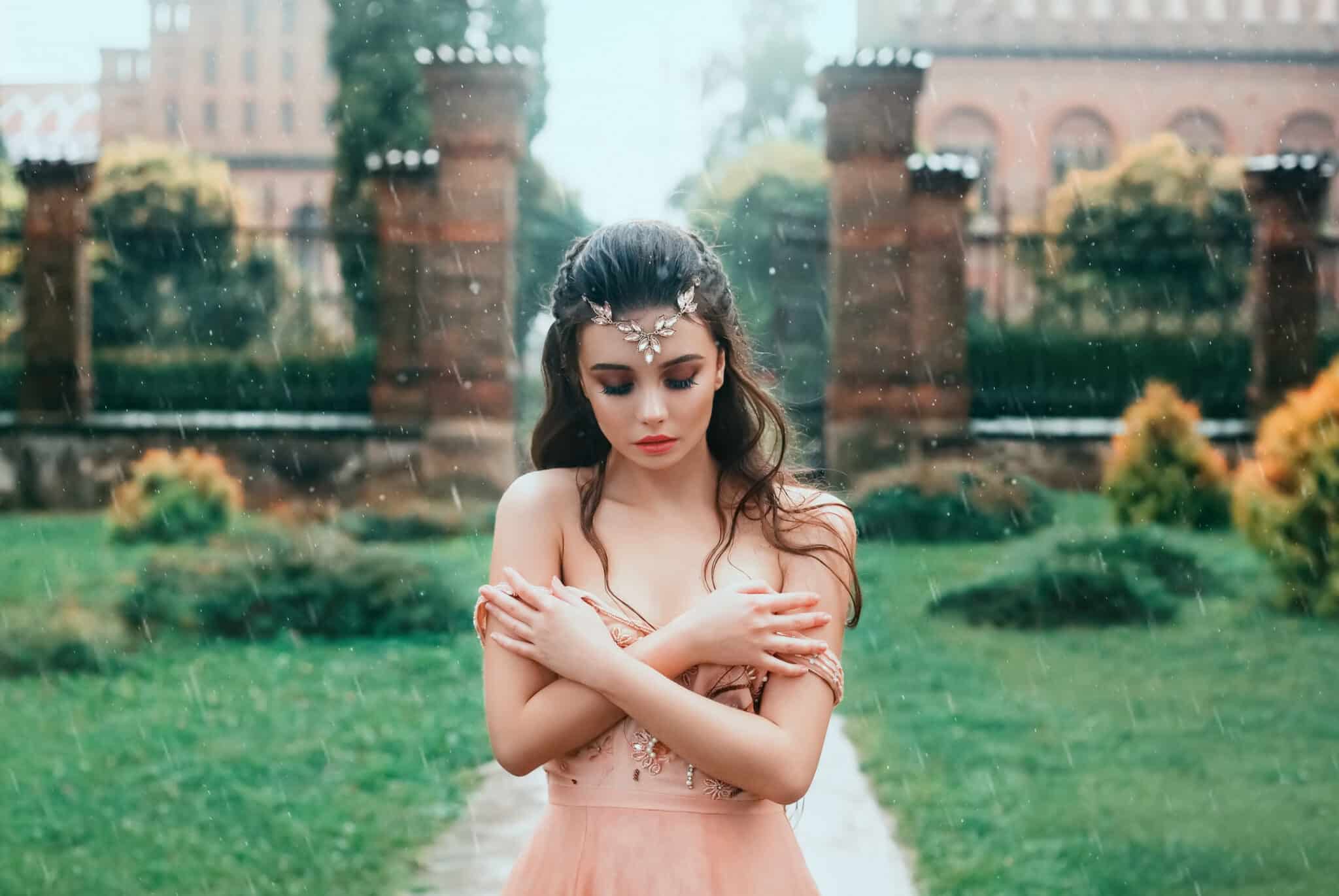 Attractive brunette girl with a cute angel face standing in the rain under the open sky. 