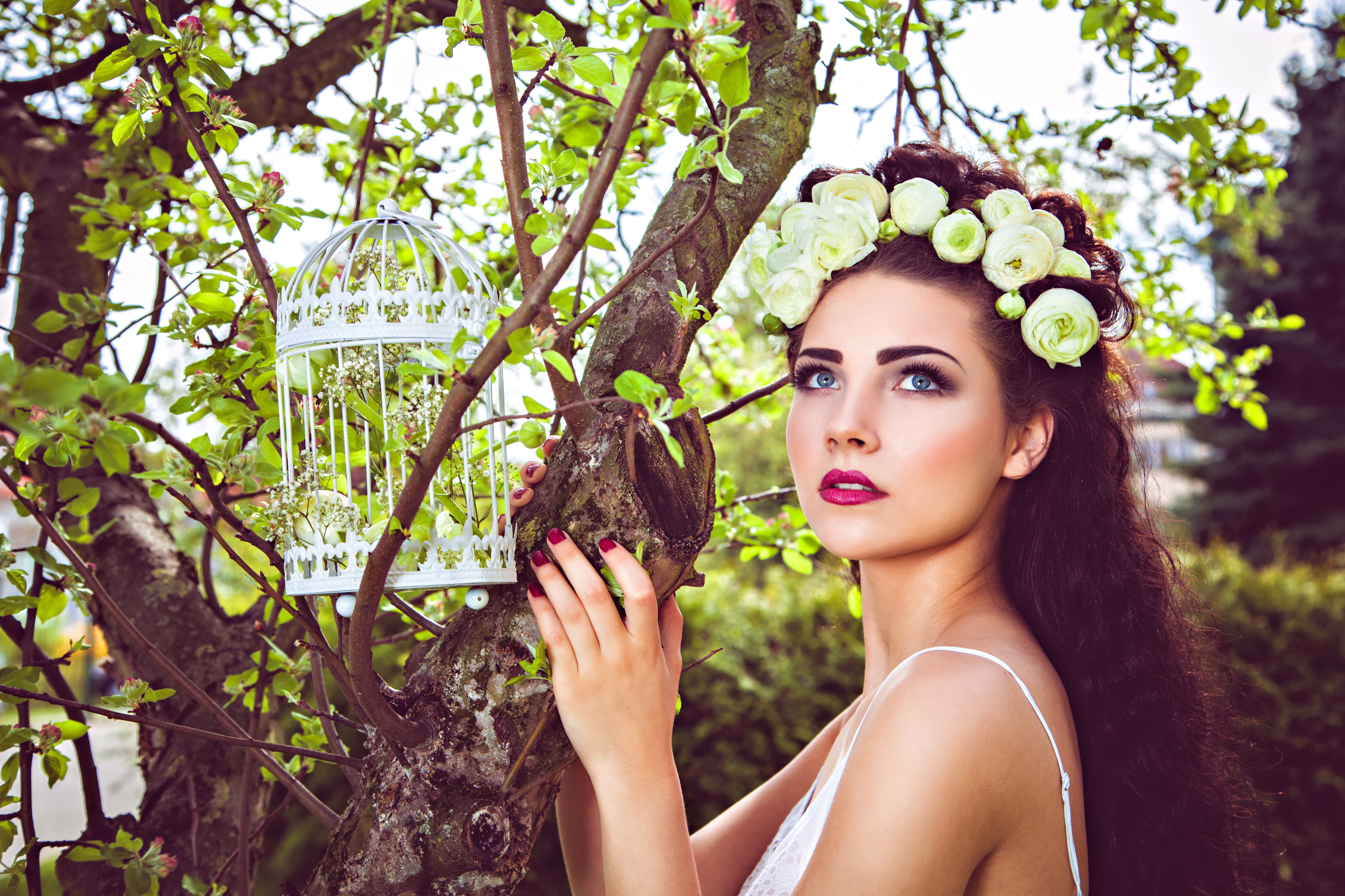 beautiful woman near tree with white flower head wreath
