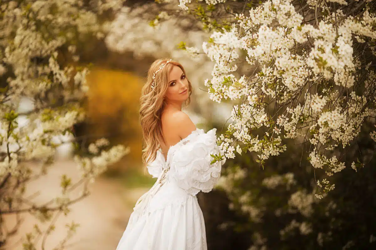 a charming lady in white dress in a spring garden