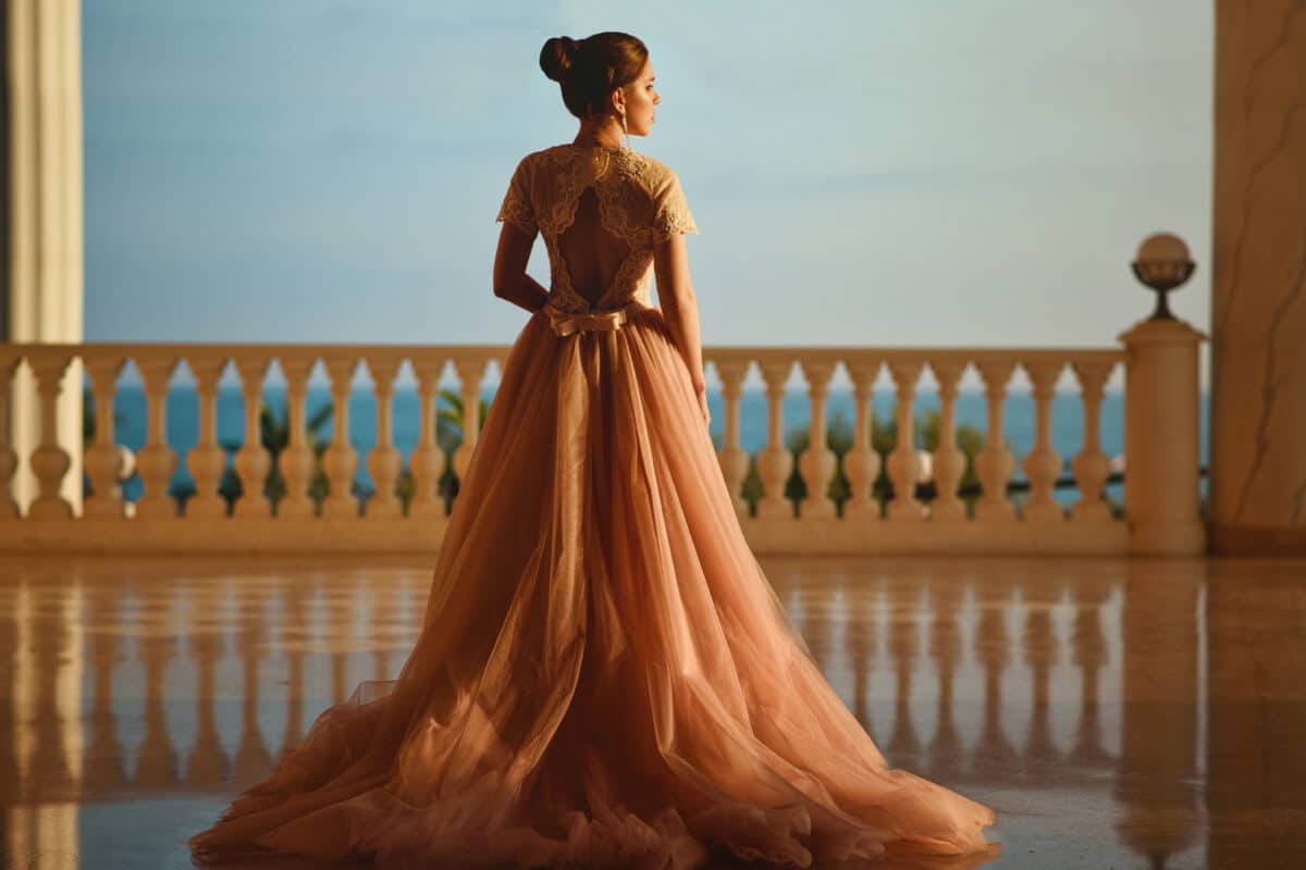 melancholic woman in luxurious ballroom dress with tulle skirt standing on the balcony