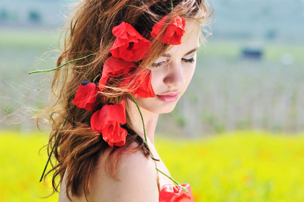 young lady standing with red poppies in her hair