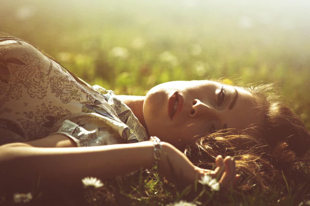 delicate beautiful young woman enjoys in sun lie in grass 
